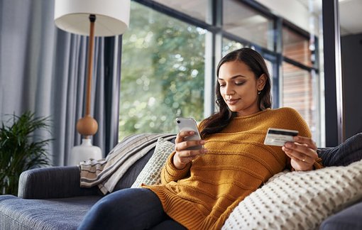woman at home shopping on her mobile device holding credit card