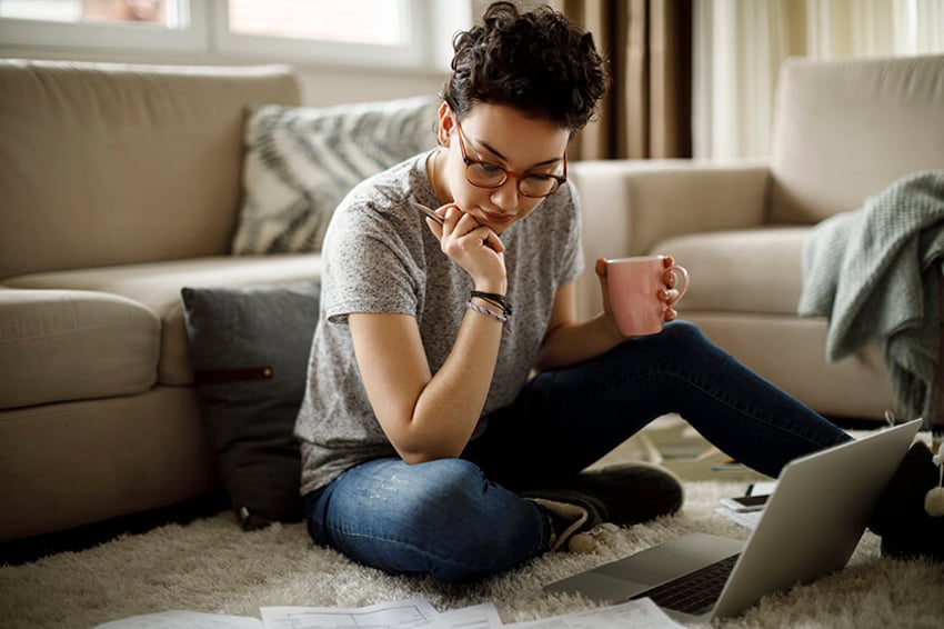 woman looking at finances on paper and laptop woman at home looking at finances on paper and laptop