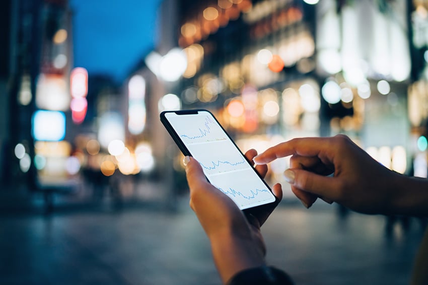 Person with phone in hand in front of city street scene at night