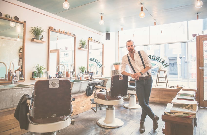 Caucasian stylist smiling in barber shop