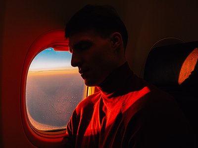 Side view of young handsome male sleeping in aircraft over window with sunset