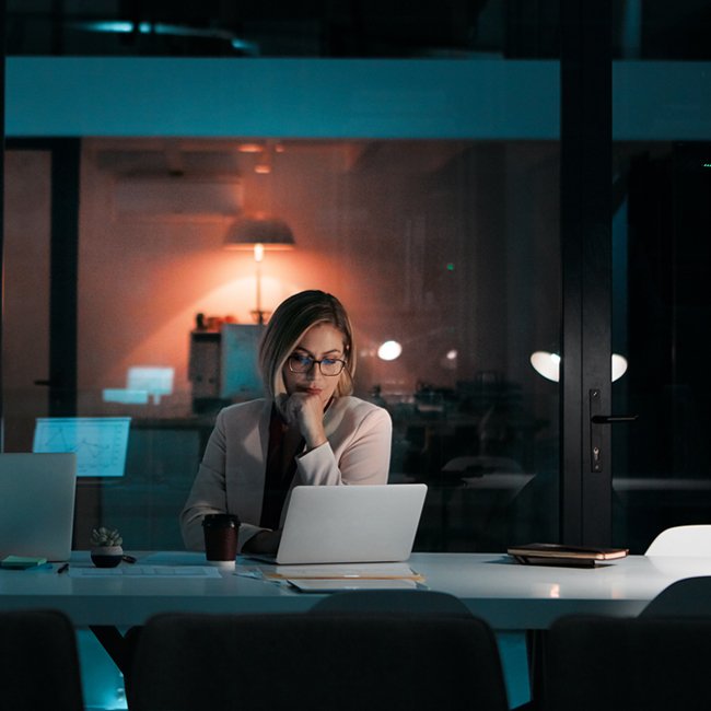Shot of a businesswoman using a laptop at her desk during a late night at work